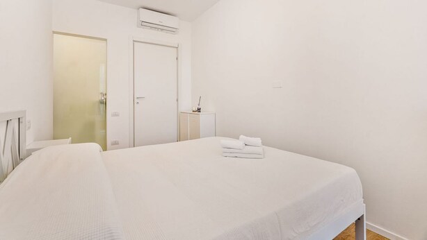 Une chambre d’hôtel comprenant un lit, une table de chevet, une armoire et un appareil de climatisation.