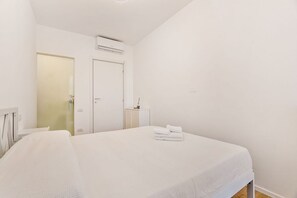 Ein Hotelzimmer mit Bett, Nachttisch, Kleiderschrank und Klimaanlage.