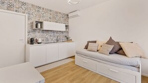 Une cuisine de taille réduite avec des meubles blancs, un plan de travail et un pare-feu décoré.