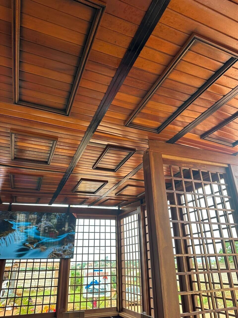 A ceiling with a geometric pattern of wooden beams and a grid-like window structure.
