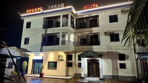 Un hotel de varios pisos con un letrero llamativo que dice 'GROUPS FOKAN HOTEL' en la parte superior.
