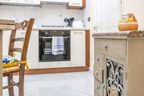 A kitchen with a gas stove, oven, and a cabinet with drawers. - Casa del Sole - Menfi (Menfi)