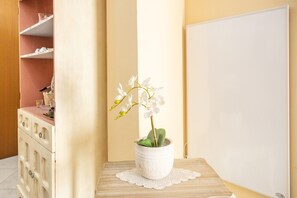 A white orchid in a pot on a wooden table with a doily, a whiteboard, and a wooden cabinet with drawers. - Casa del Sole - Menfi (Menfi)