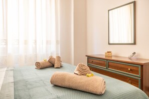 A hotel room with a bed, a wooden dresser, a mirror, and a window with curtains. - Casa del Sole - Menfi (Menfi)