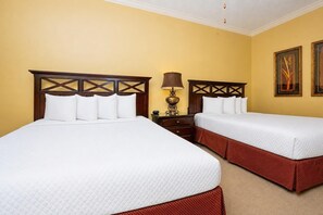Habitación de hotel con dos camas, una mesita de noche, una lámpara y dos cuadros en la pared.
