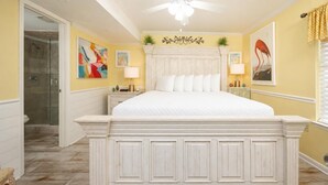 A bedroom with a white bed, a glass shower enclosure, and a colorful rug. - Phoenix Iii 3073 1 Bedroom Condo (Orange Beach)
