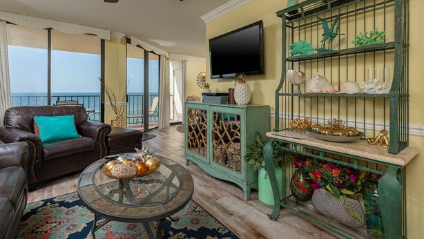 A living room with a leather sofa, a glass coffee table, a television, and a decorative birdcage. - Phoenix Iii 3073 1 Bedroom Condo (Orange Beach)