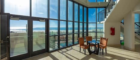 A spacious room with large floor-to-ceiling windows offering a view of the beach and ocean.