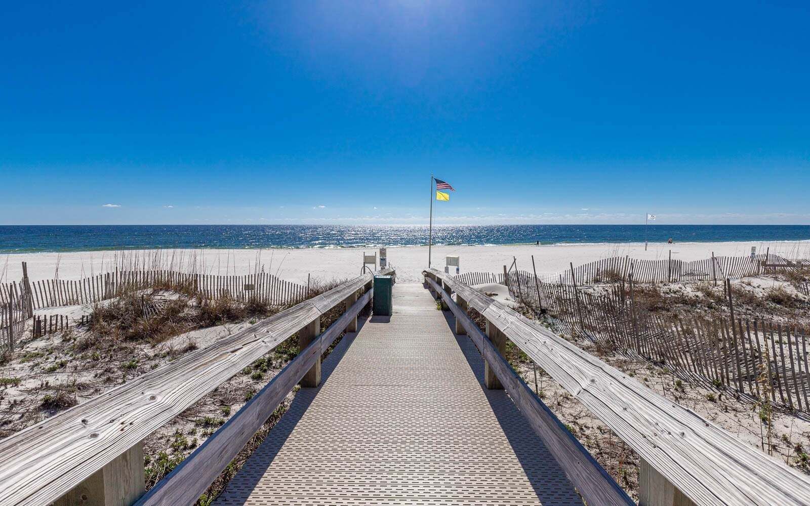 Un muelle de madera que lleva a una playa con una bandera.