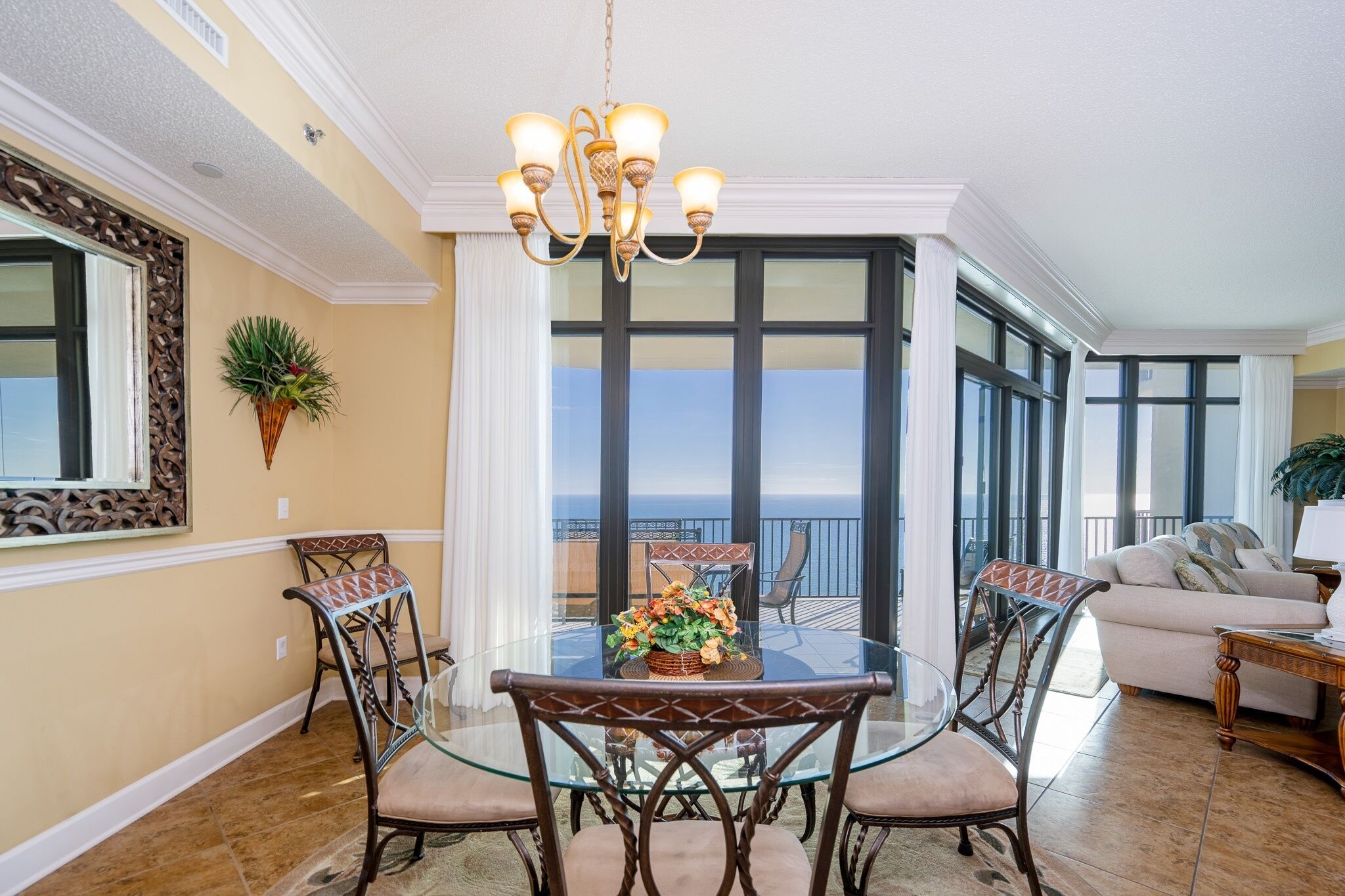 A dining area with a glass table, chairs, and a chandelier.