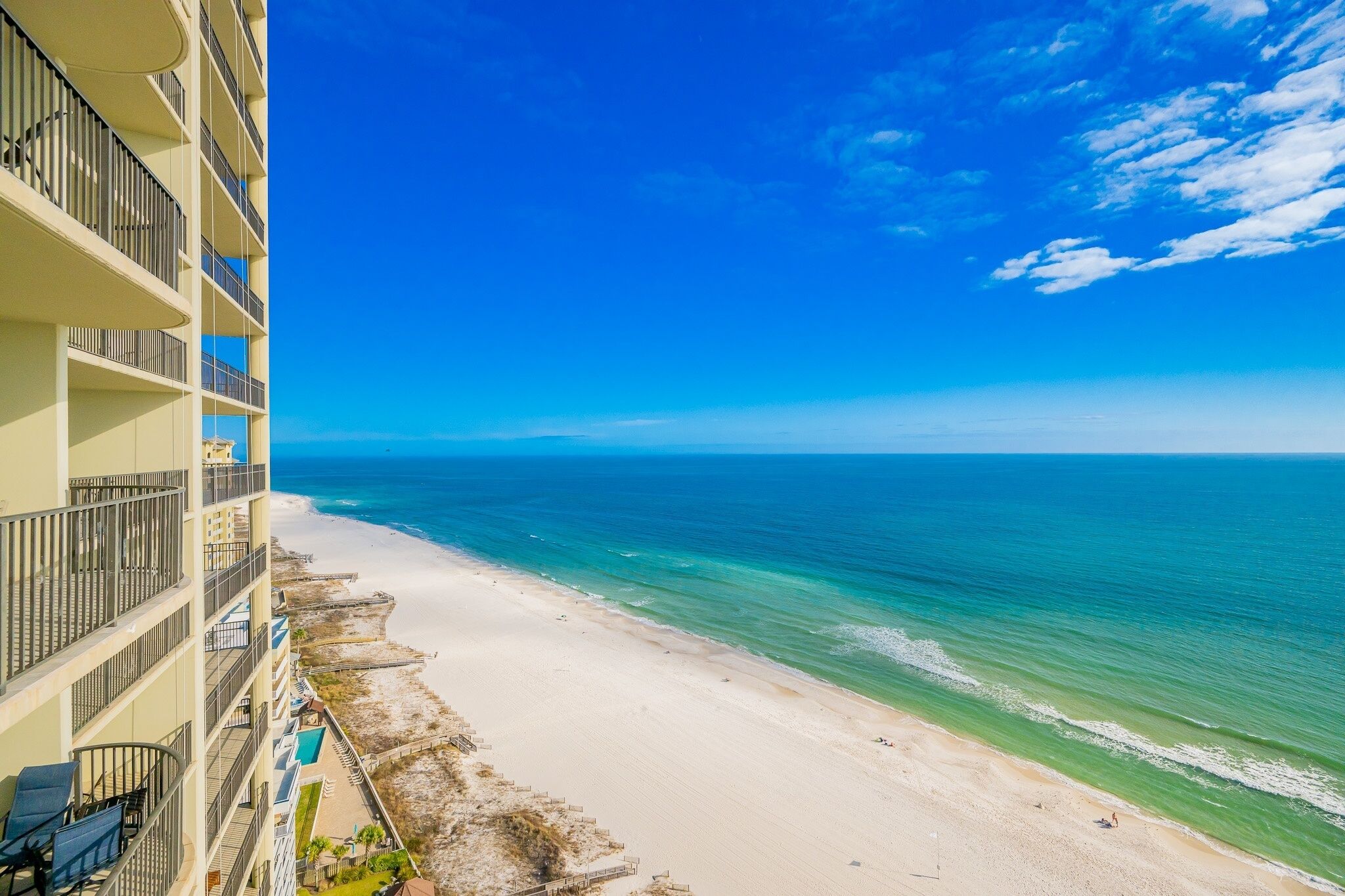 Un hôtel situé en bord de mer, doté de nombreux balcons, d’une plage de sable et offrant une vue dégagée sur l’océan.