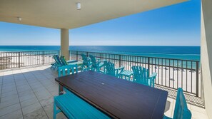 Un balcon avec vue sur la plage, une table et des chaises.