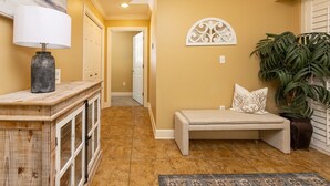 A hallway with a bench, a lamp, a potted plant, and a decorative wall piece. - Phoenix West 1701 4 Bedroom Condo (Orange Beach)