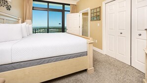 A hotel room with a large bed, a view of the sea, and a set of white doors. - Phoenix West 1701 4 Bedroom Condo (Orange Beach)