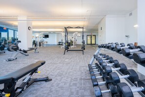 Ein Fitnessstudio mit verschiedenen Trainingsgeräten, darunter Hanteln, Bänke und Kraftgeräte.