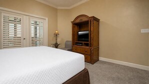 A bedroom with a large bed, a wooden TV stand, and a chair. - Phoenix West 1006 3 Bedroom Condo (Orange Beach)