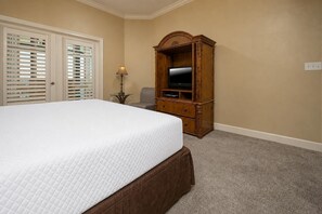Ein Schlafzimmer mit einem großen Bett, einem Holz-Fernseherstand und einem Sessel.