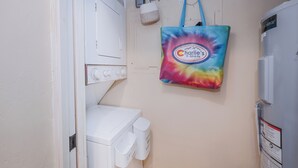Een wasserette met een witte wasmachine, een droger en een blauwe opbergzak aan de muur.