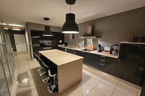 A modern kitchen with a central island, black cabinets, and stainless steel appliances. - A magnificent five-bedroom villa, just a few minutes' walk from downtown. (L'Isle-sur-la-Sorgue)