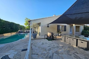 A poolside area with a stone patio, outdoor furniture, and a shaded seating area. - A magnificent five-bedroom villa, just a few minutes' walk from downtown. (L'Isle-sur-la-Sorgue)