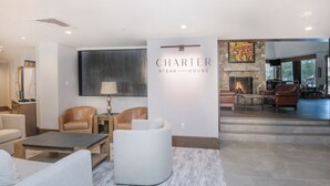 Una sala de estar moderna con chimenea, sillones de cuero, una mesa de centro y una pared de acento de piedra.