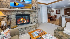 Una sala de estar con chimenea de piedra, un televisor de pantalla plana montado en la pared y un juego de Scrabble sobre la mesa de centro.