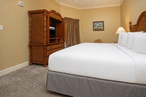 A hotel room with a large bed, a wooden wardrobe, a television, and a painting on the wall. - Phoenix West 906 3 Bedroom Condo (Orange Beach)