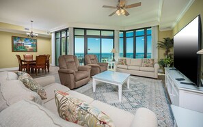 A living room with a sofa, armchairs, a coffee table, a TV, and a balcony with a view. - Phoenix West 2506 3 Bedroom Condo (Orange Beach)