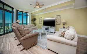 Ein modernes Wohnzimmer mit großem Flachbildfernseher, zwei Sofas, einem Couchtisch und einem Deckenventilator.