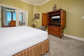 Ein Hotelzimmer mit einem großen Bett, einem Holzschrank, einem Fernseher und einem Fenster mit Jalousien.