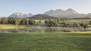 A lakeside view with a grassy foreground, a small dock, and a mountain range in the background. - Superior Apartment # B8 with 3 bedrooms and sauna (Söll)