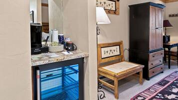 A compact room with a kitchenette, a wooden chair, a cabinet, and a patterned rug.