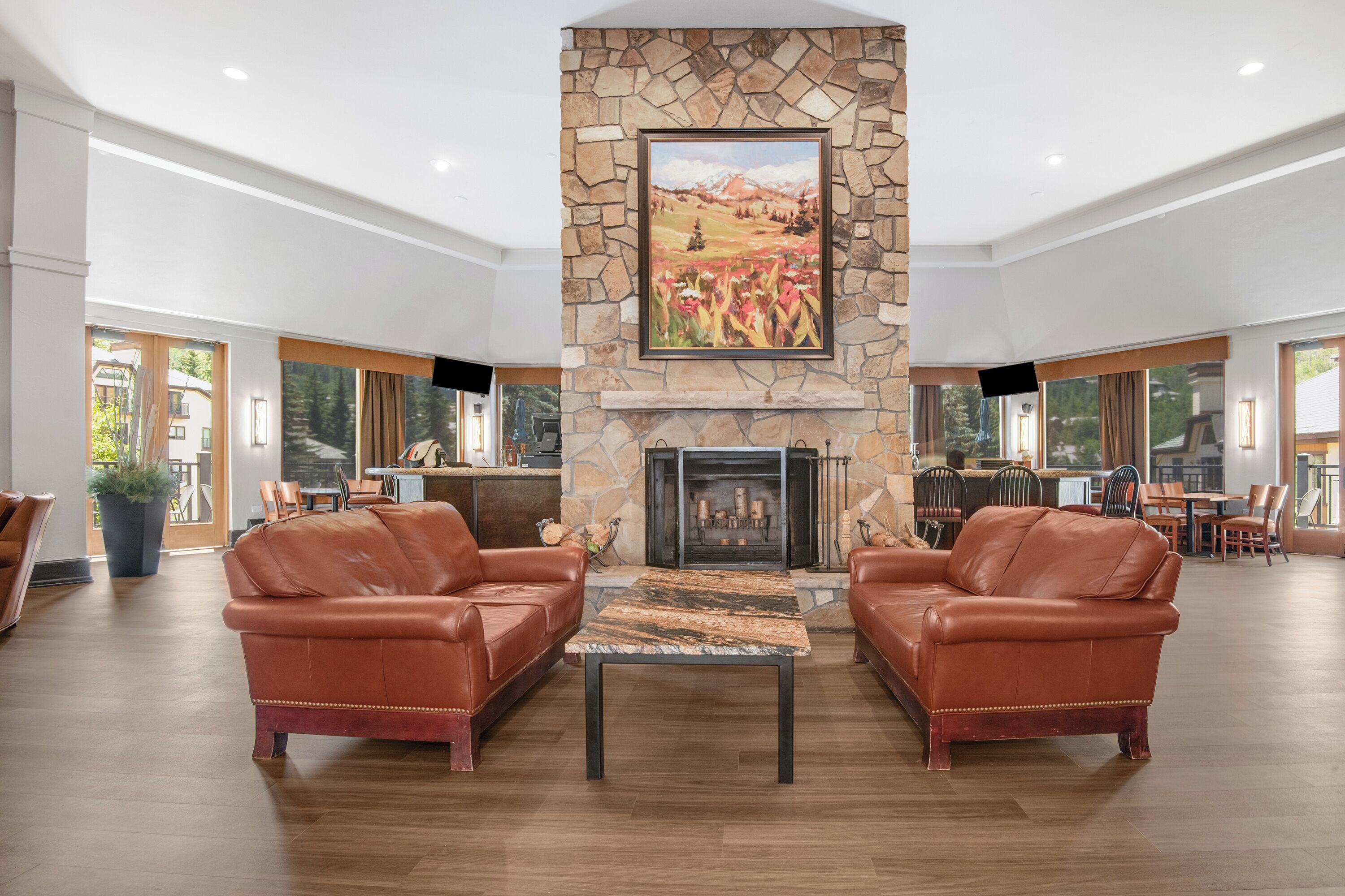 A spacious lobby with a stone fireplace, leather sofas, and a dining area.