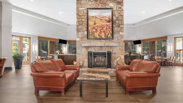 A spacious lobby with a stone fireplace, leather sofas, and a dining area.