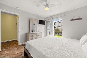 A bedroom with a bed, a dresser, a television, and a ceiling fan. - Wendwood F2 | Walk to the Beach • Community Pool • Sleeps 5 (Panama City Beach)