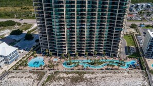 Un hotel de gran altura con varios balcones, una zona de piscina y una playa.