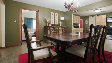 A dining room with a large wooden table and chairs, a chandelier, and a red carpet.