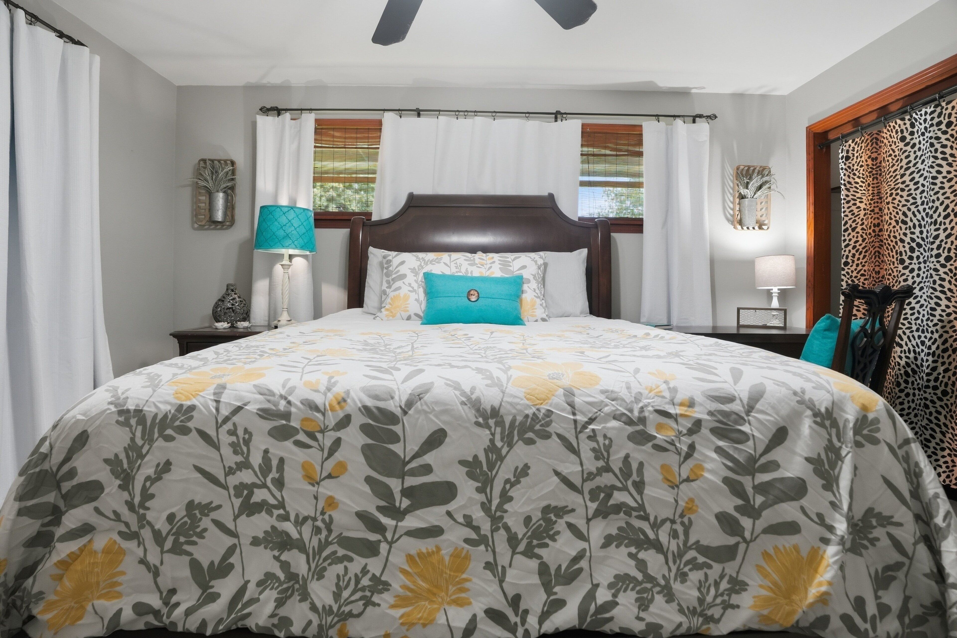 A bedroom with a large bed, a nightstand, a lamp, and a chair.