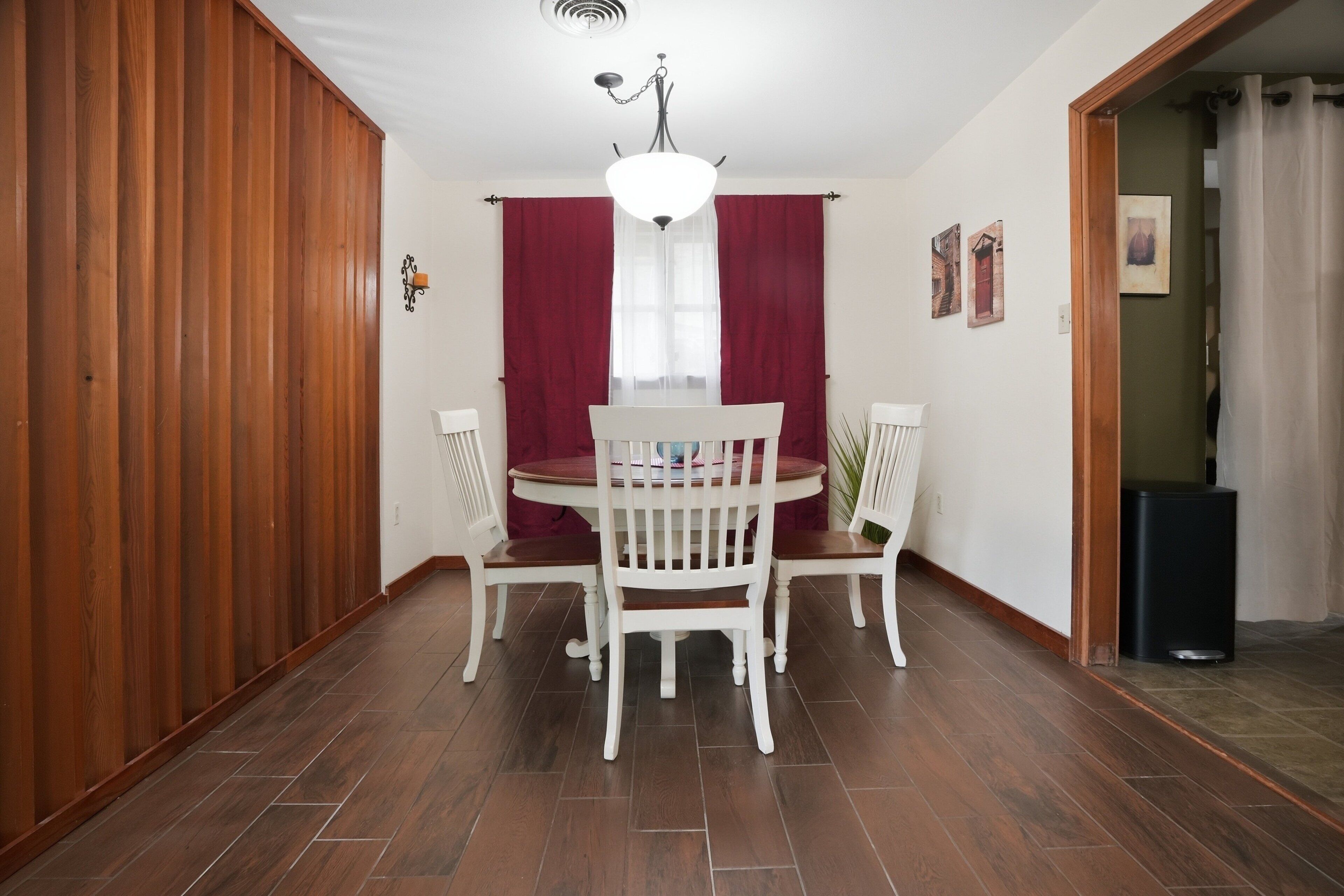 Un coin repas avec une table ronde, des chaises blanches et un lustre.