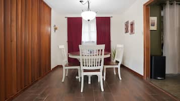 Un coin repas avec une table ronde, des chaises blanches et un lustre.