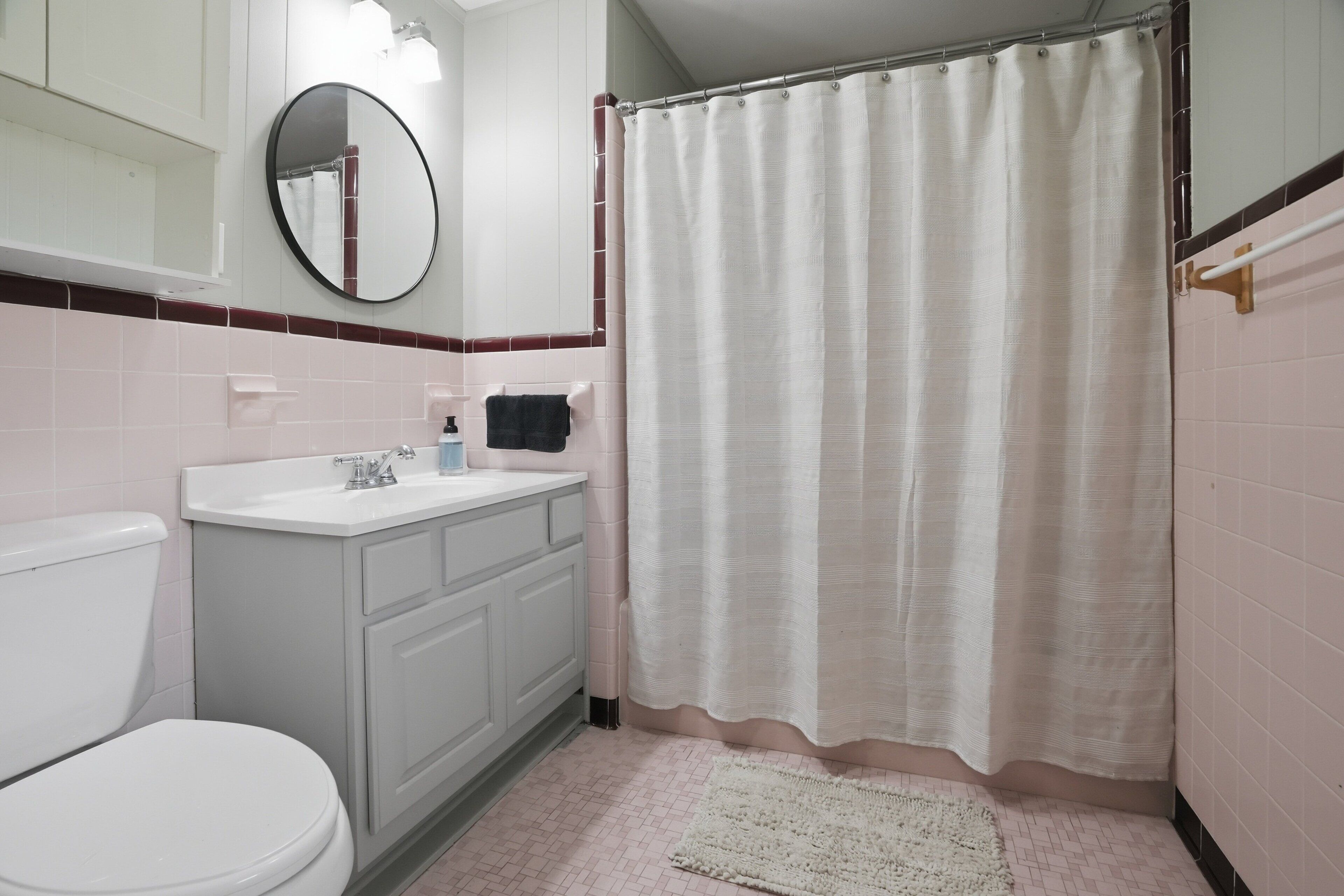 A bathroom with a toilet, sink, mirror, and shower curtain.