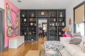 Ein modernes Wohnzimmer mit einer großen Bücherwand, einem Essbereich und einer Wand in Rosa.