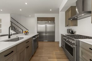 Eine moderne Küche mit Edelstahlgeräten, Holzschränken und einer weißen Arbeitsplatte.