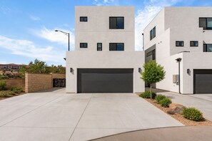 A modern two-story residential building with a garage, a landscaped driveway, and a clear sky. - Courtside Sunsets 5 Bedroom Townhouse (St. George)