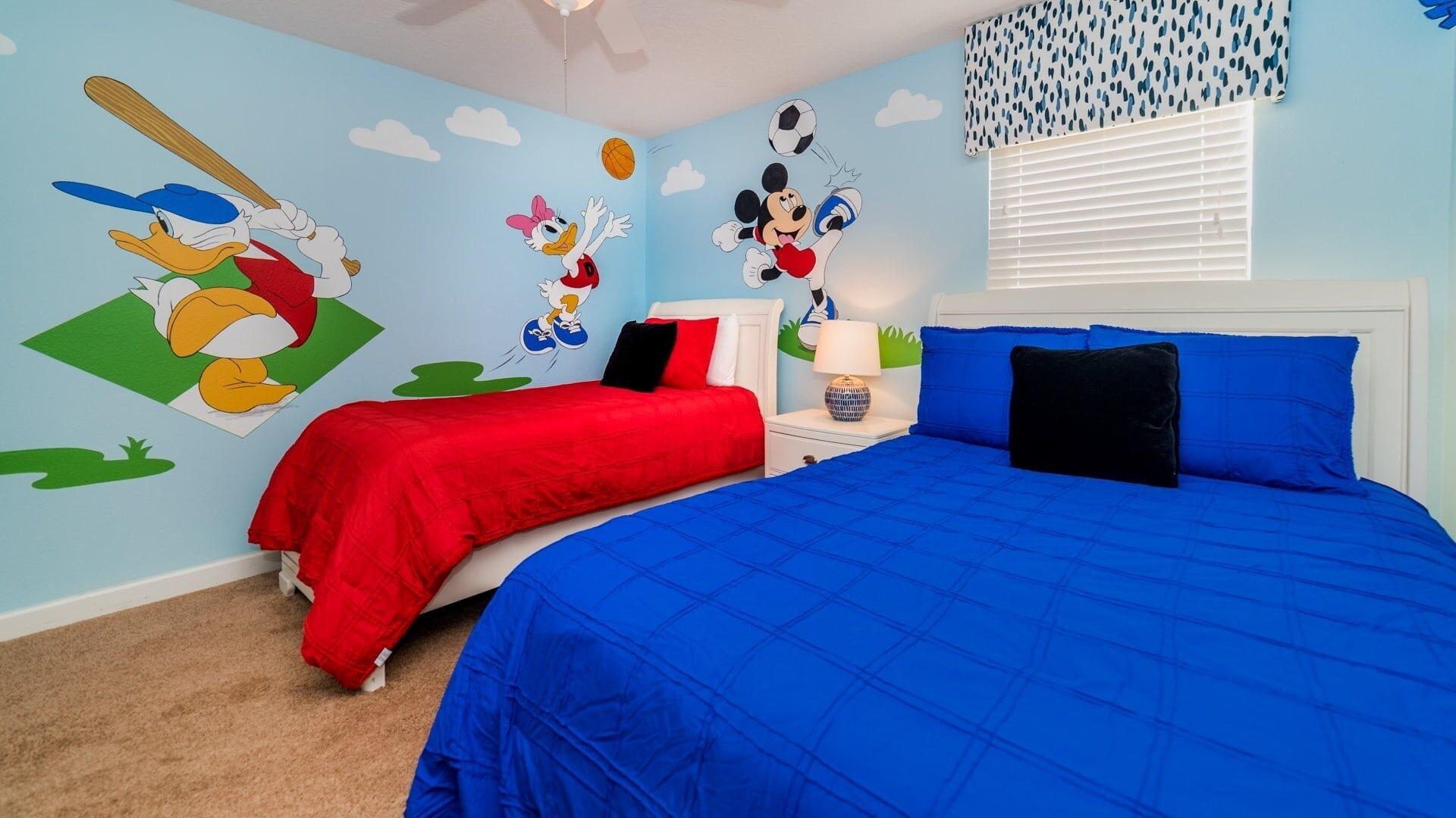 A bedroom with two beds, one with red bedding and the other with blue bedding.