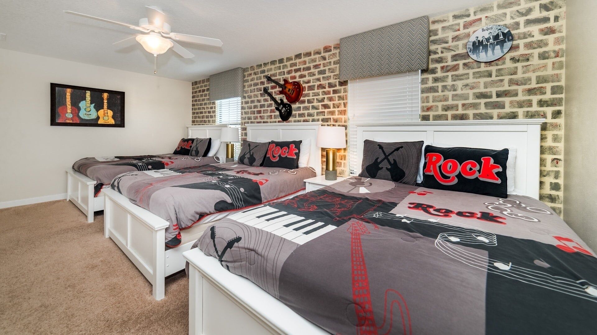 A bedroom with two beds, a brick wall, a ceiling fan, and a wall clock.