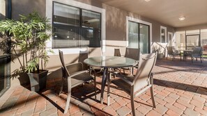 An outdoor patio with a glass table and chairs, surrounded by potted plants and a brick floor. - Wex1412 9 Bedroom Home (Davenport)