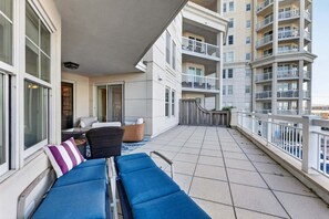 A balcony with a sofa, chairs, and a table, overlooking a residential building. - Residence 109 at The Grand (Wildwood)