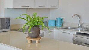 Eine moderne Küche mit weißen Schränken, einer Mikrowelle, einer Kaffeemaschine und einem Spülbecken.