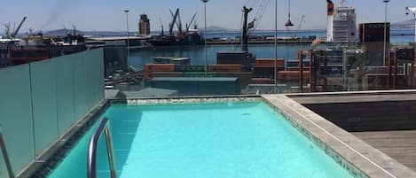 Una piscina con vista a un puerto y grúas al fondo.
